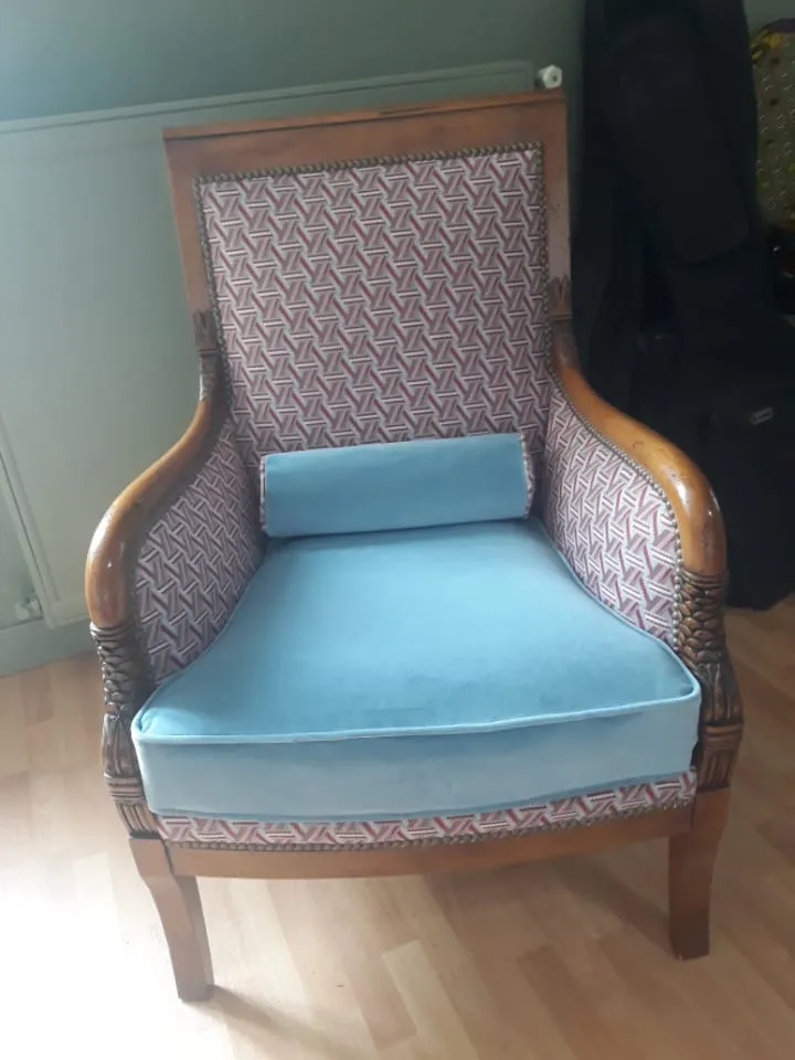 Bergère en bois aux accoudoirs sculptés, garnie d'un velours bleu et d'un tissu géométrique