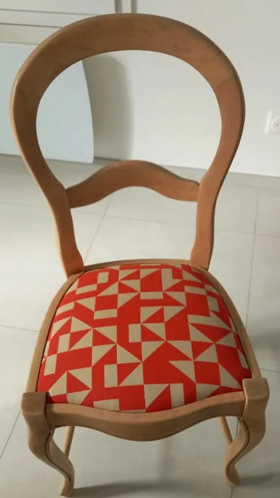 Chaise en bois clair, assise garnie d'un tissu géométrique rouge et beige