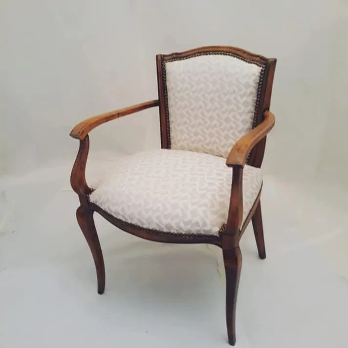 Fauteuil ancien en bois fruitier retapissé d'un tissu beige texturé, sur fond clair